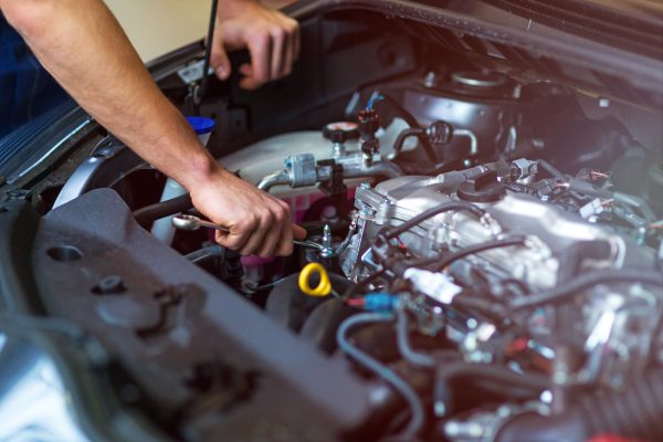 dreamstime_m_105779070 Hands of mechanic working on car engine in auto repair shop